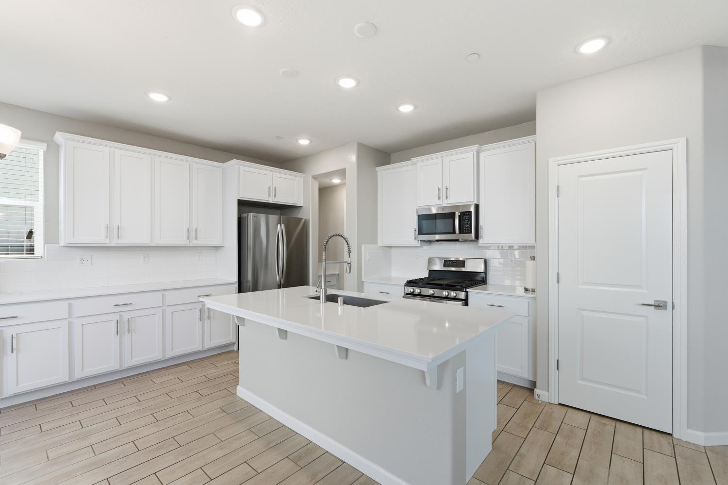1107 Significant Way West Madera, CA 93636 - Photo 16 of 42 a kitchen with white cabinets and stainless steel appliances