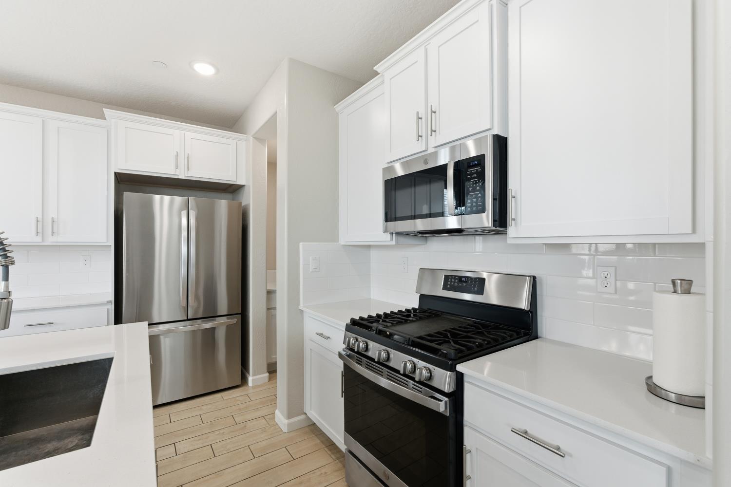 1107 Significant Way West Madera, CA 93636 - Photo 17 of 42 a kitchen with cabinets stainless steel appliances and wooden floor