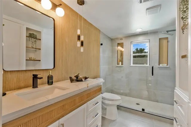 a bathroom with a granite countertop sink toilet and mirror