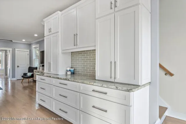 a view of kitchen with granite countertop white cabinets and sink