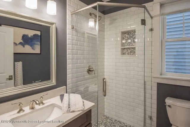 a bathroom with a granite countertop sink a toilet and shower