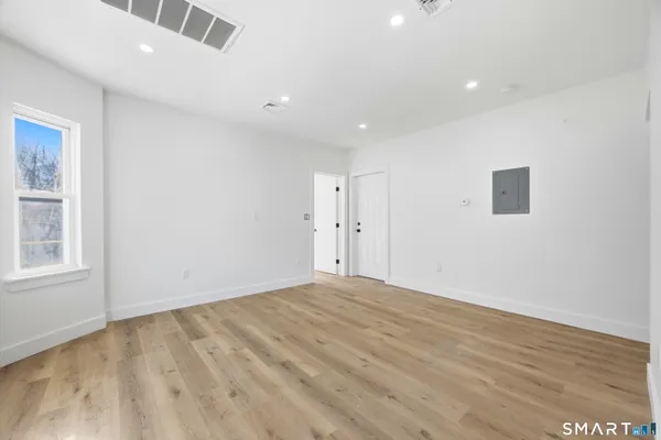 an empty room with wooden floor and windows