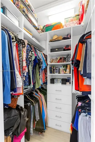 a view of walk in closet with clothes and shoes