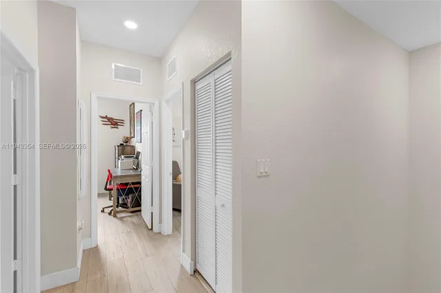 a view of a hallway with wooden floor and closet