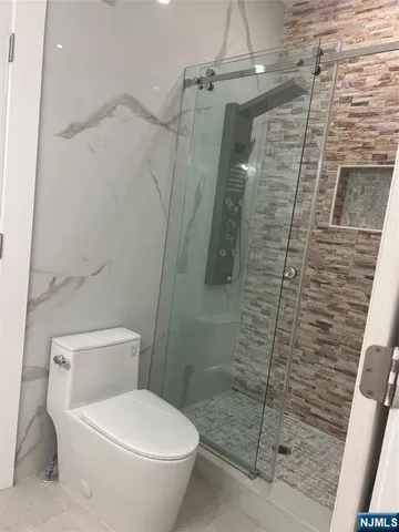 a bathroom with a granite countertop sink a toilet and with shower