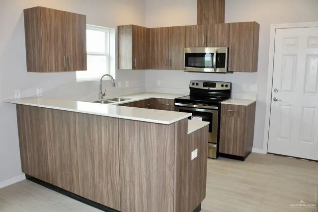 a kitchen with stainless steel appliances a stove a sink a microwave a refrigerator and cabinets