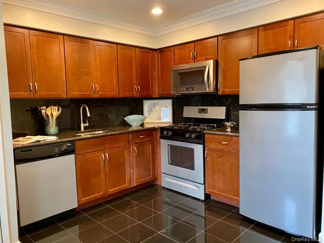 a kitchen with stainless steel appliances granite countertop a refrigerator a sink and white cabinets