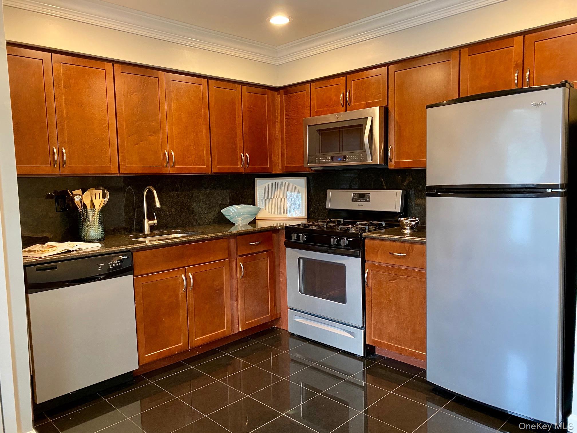 32 Country Club Drive, Unit 32C Coram, NY 11727 - Photo 2 of 8 a kitchen with stainless steel appliances granite countertop a refrigerator a sink and white cabinets