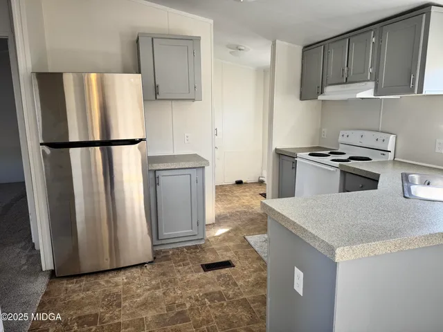 a kitchen with stainless steel appliances granite countertop a refrigerator a stove and a sink