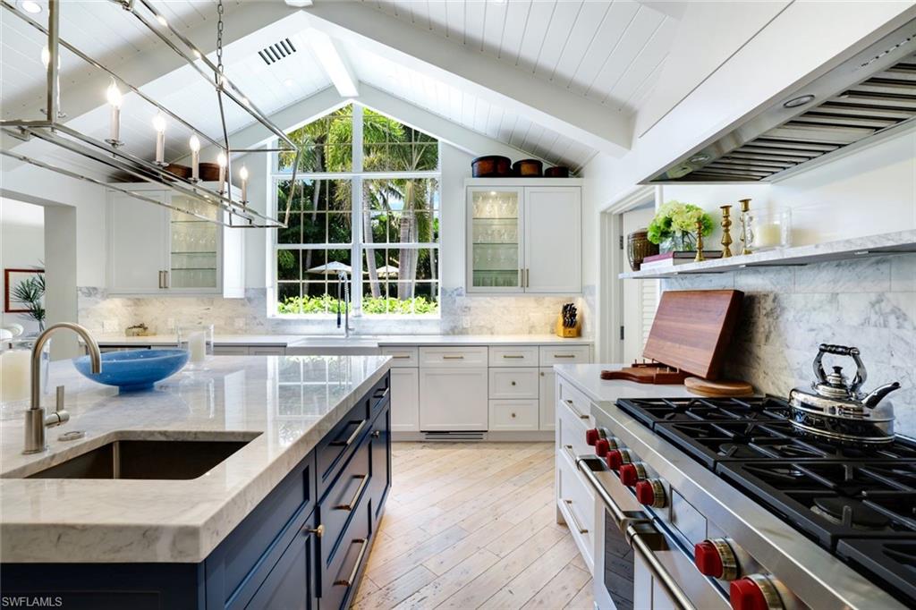 642 6th Avenue North Naples, FL 34102 - Photo 11 of 25 Kitchen featuring under cabinet range hood, premium stove, pendant lighting, glass insert cabinets, and white cabinets