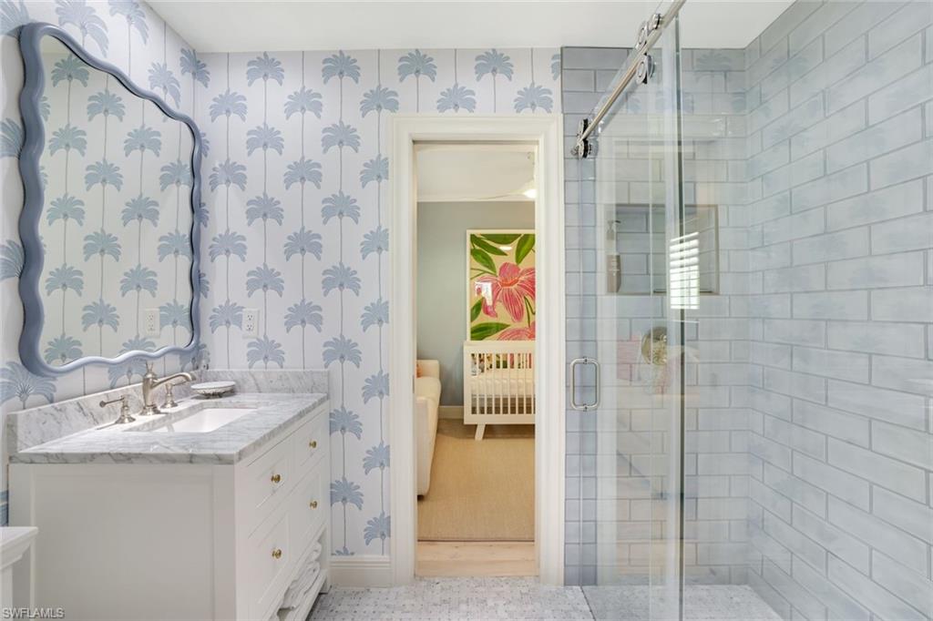642 6th Avenue North Naples, FL 34102 - Photo 19 of 25 Ensuite bathroom featuring wallpapered walls, a stall shower, and vanity