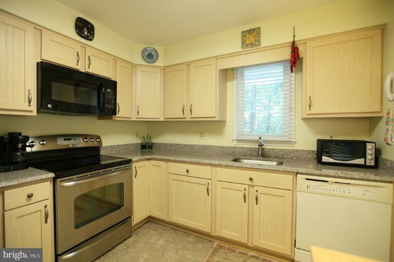 1521 Church Hill Place, Unit 1521 Reston, VA 20194 - Photo 2 of 20 a kitchen with stainless steel appliances granite countertop white cabinets a sink a stove a microwave and wooden cabinets