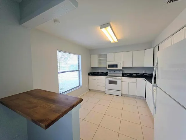 a white kitchen with granite countertop white cabinets and white appliances