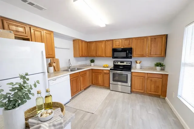 a kitchen with a refrigerator a stove top oven a sink and dishwasher with wooden floor