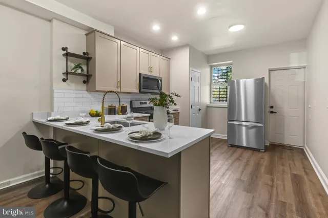 a kitchen with stainless steel appliances a stove a refrigerator a sink a dining table and chairs