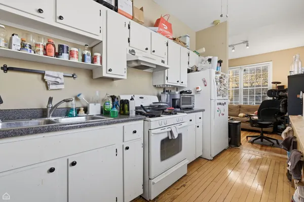a kitchen with stainless steel appliances granite countertop a stove a sink dishwasher and white cabinets next to a window