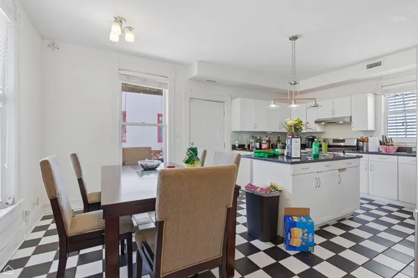a kitchen with a dining table chairs and white cabinets