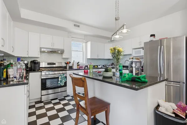 a kitchen with stainless steel appliances granite countertop a refrigerator a sink a stove a dining table and chairs