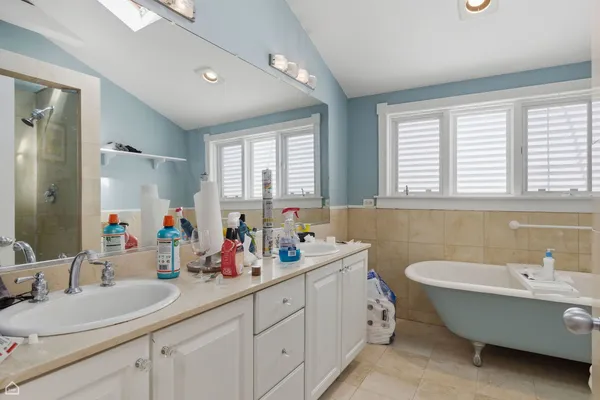 a bathroom with double vanity sinks a mirror and a bathtub next to a window