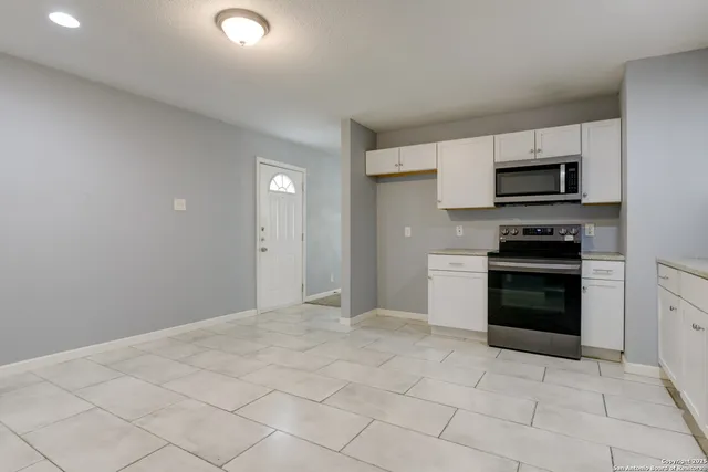 a kitchen with granite countertop a stove top oven and cabinets