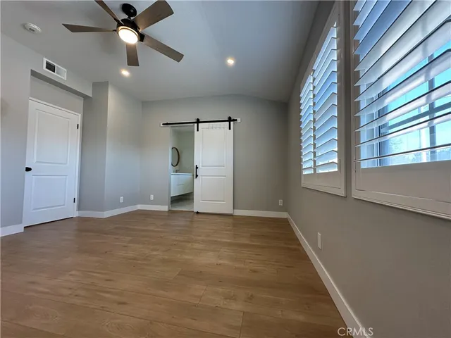 an empty room with wooden floor fan and windows