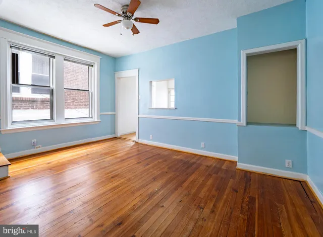 an empty room with wooden floor and windows