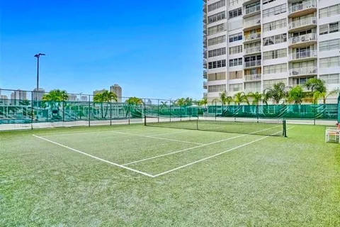 a view of a tennis ground with a large trees