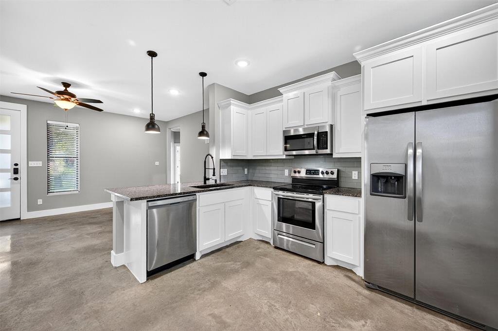 1501 South 7th Avenue Denison, TX 75021 - Photo 12 of 32 a kitchen with granite countertop a refrigerator oven a sink and white cabinets