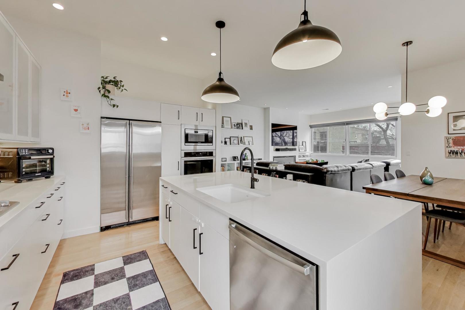4410 North Troy Street, Unit 301 Chicago, IL 60625 - Photo 8 of 23 a kitchen with stainless steel appliances a stove a refrigerator a oven a sink with a dining table and chairs