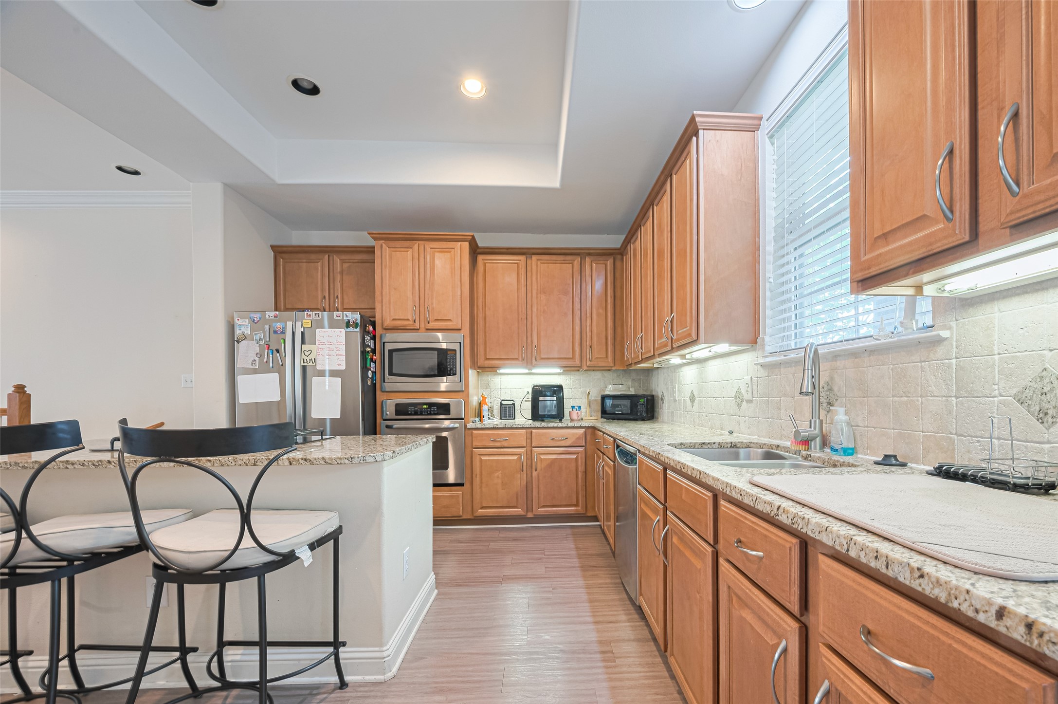24 Versante Court Houston, TX 77070 - Photo 30 of 30 a kitchen with stainless steel appliances granite countertop white cabinets a sink dishwasher a stove and a refrigerator with wooden floor