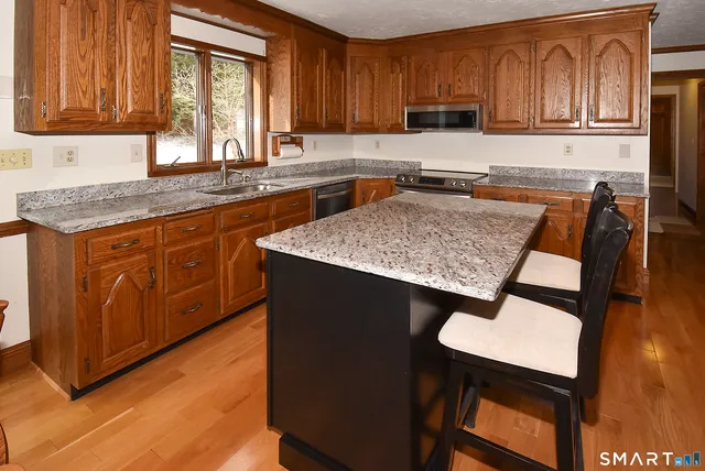a kitchen with stainless steel appliances granite countertop wooden floor a dining table and chairs