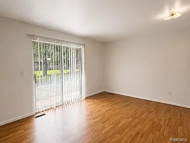 48770 Shelby Road, Unit 13 Utica, MI 48317 - Photo 8 of 10 Spacious room featuring wood-finish flooring, white baseboards, and a sliding glass door with vertical blinds