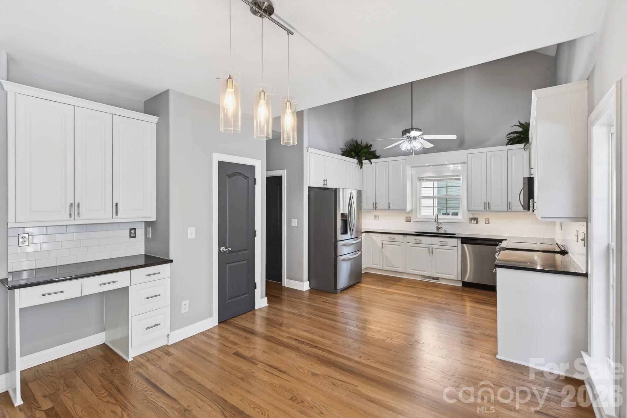 9101 Pitcairn Drive Tega Cay, SC 29708 - Photo 18 of 48 a kitchen with stainless steel appliances kitchen island granite countertop a refrigerator a sink dishwasher a stove and white cabinets with wooden floor