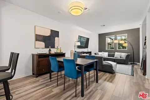 a kitchen with stainless steel appliances white cabinets a sink a stove a dining table and chairs