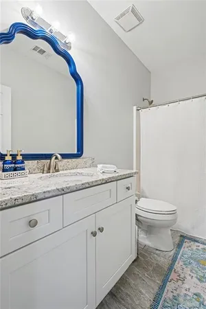 a bathroom with a granite countertop toilet sink and mirror