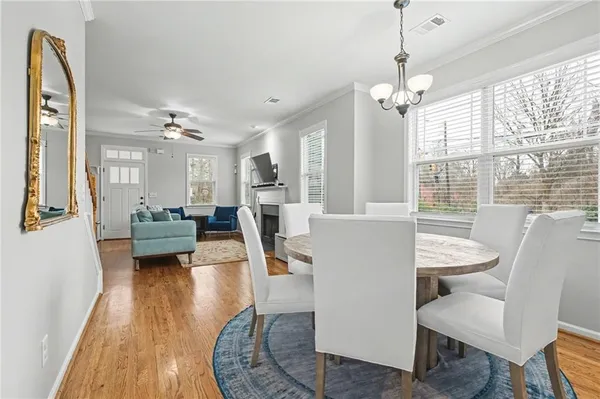 a living room with furniture dining table wooden floor and a chandelier