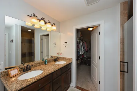 a bathroom with a granite countertop sink a mirror and a shower
