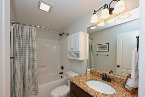 a bathroom with a granite countertop sink mirror toilet and bathtub