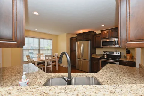 a kitchen with granite countertop a refrigerator and a stove top oven