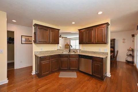 a kitchen with stainless steel appliances granite countertop wooden cabinets granite counter tops and a hard wood floors