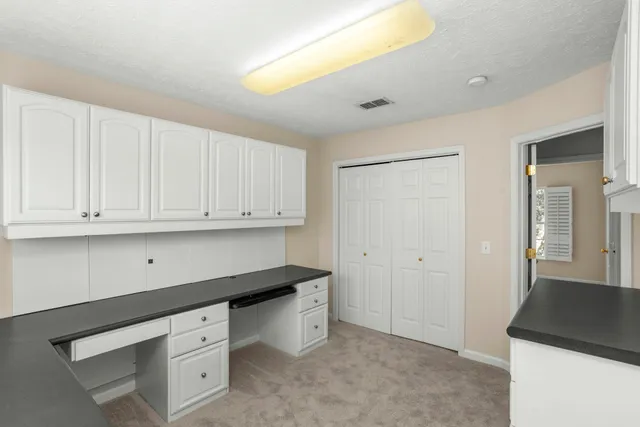 wooden floor with white cabinets and window