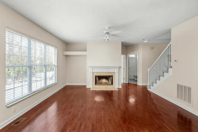 a view of an empty room with wooden floor fireplace and a window