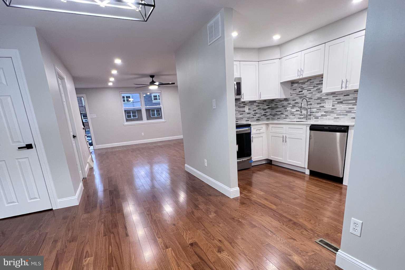 a kitchen with kitchen island granite countertop wooden floors and white cabinets