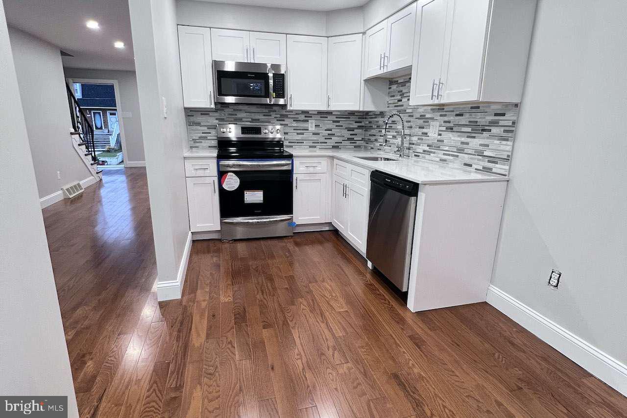 1225 Rainer Road Brookhaven, PA 19015 - Photo 13 of 15 a kitchen with wooden floors and stainless steel appliances