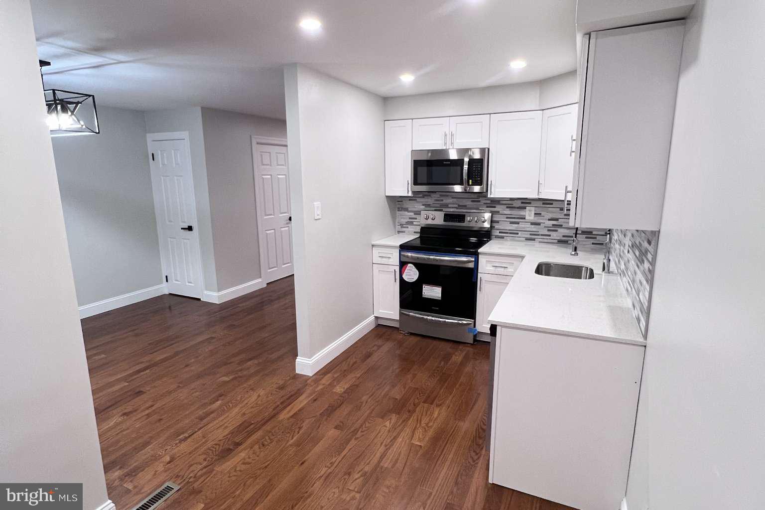 1225 Rainer Road Brookhaven, PA 19015 - Photo 15 of 15 a kitchen with kitchen island wooden floors appliances and cabinets