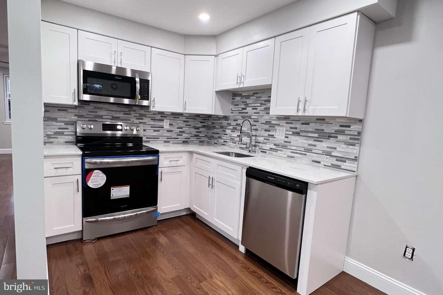 1225 Rainer Road Brookhaven, PA 19015 - Photo 5 of 15 a kitchen with granite countertop a stove top oven microwave and cabinets