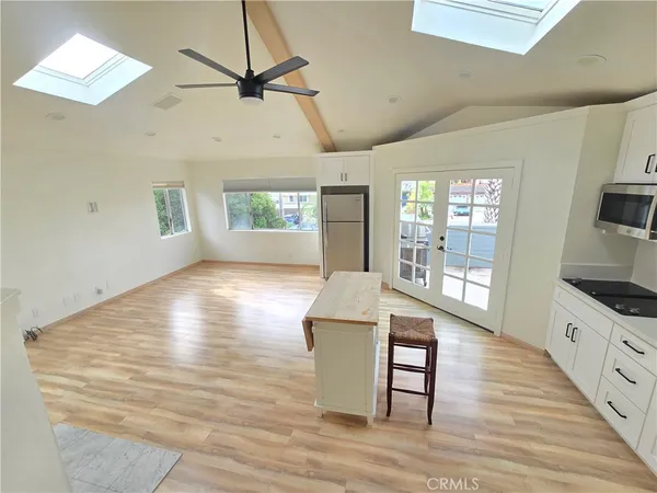 a view of an empty room and window wooden floor and a kitchen