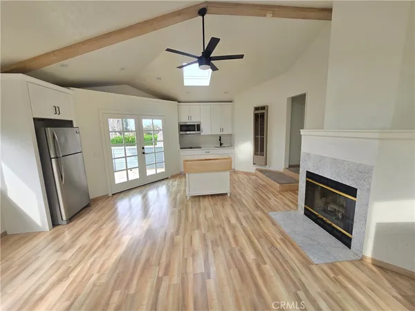 a living room with stainless steel appliances wooden floors and fireplace