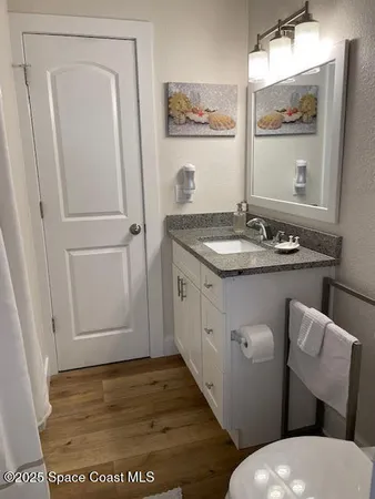 a bathroom with a granite countertop sink toilet and mirror