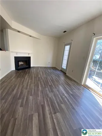 a view of empty room with wooden floor and fireplace